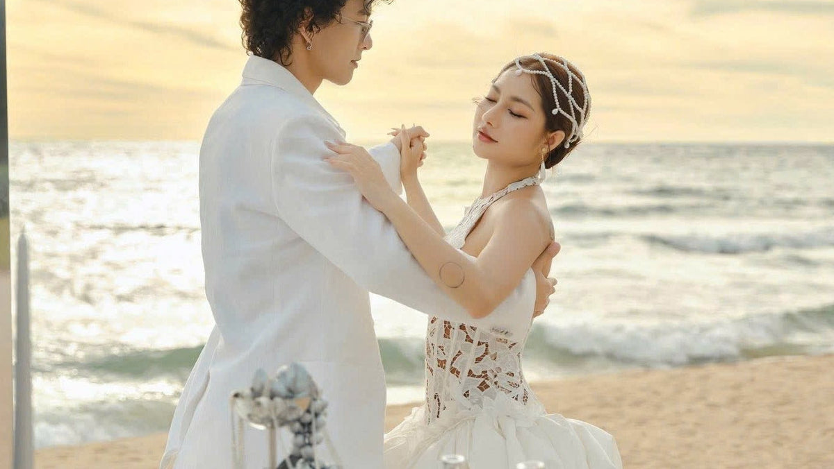 Couple embracing on a beach with a scenic ocean view.