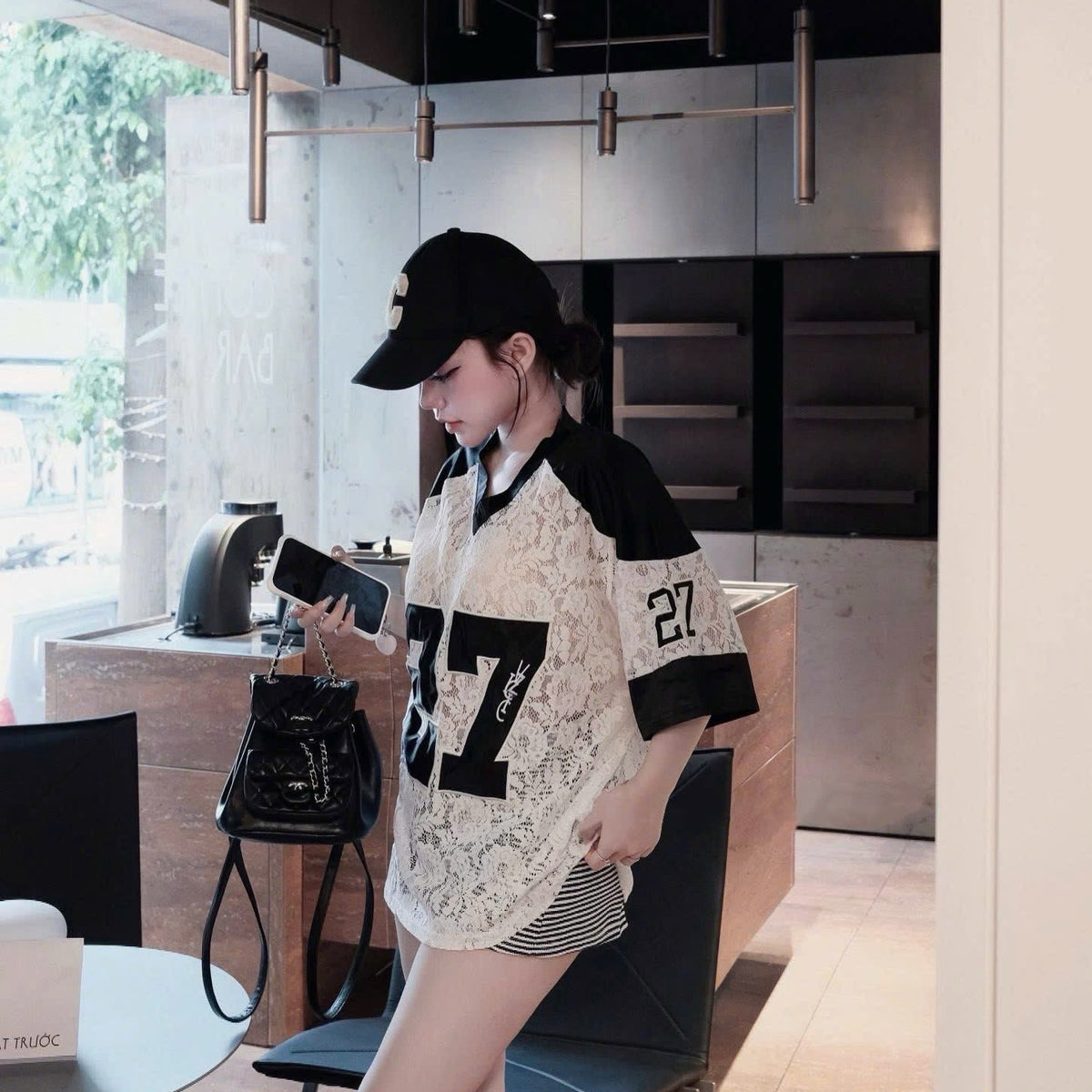 Woman in a stylish outfit with a cap and lace top in an indoor setting