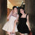 Two women in formal dresses standing close together in a hallway.